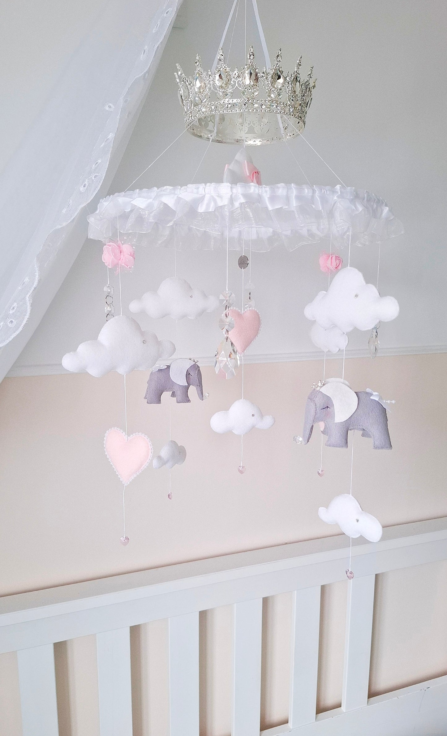 Baby girl mobile featuring handcrafted elephants with crowns, floating clouds, and soft pink heart accents.