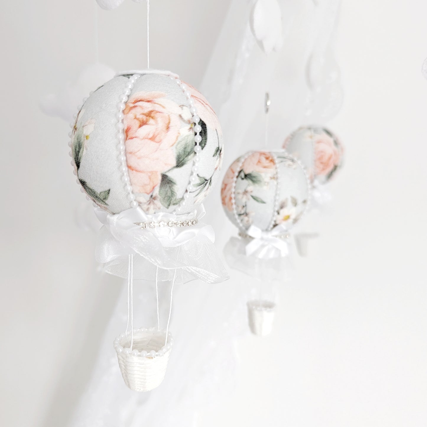 Close-up of a blush floral hot air balloon with lace and ribbon detailing on a handmade baby mobile.