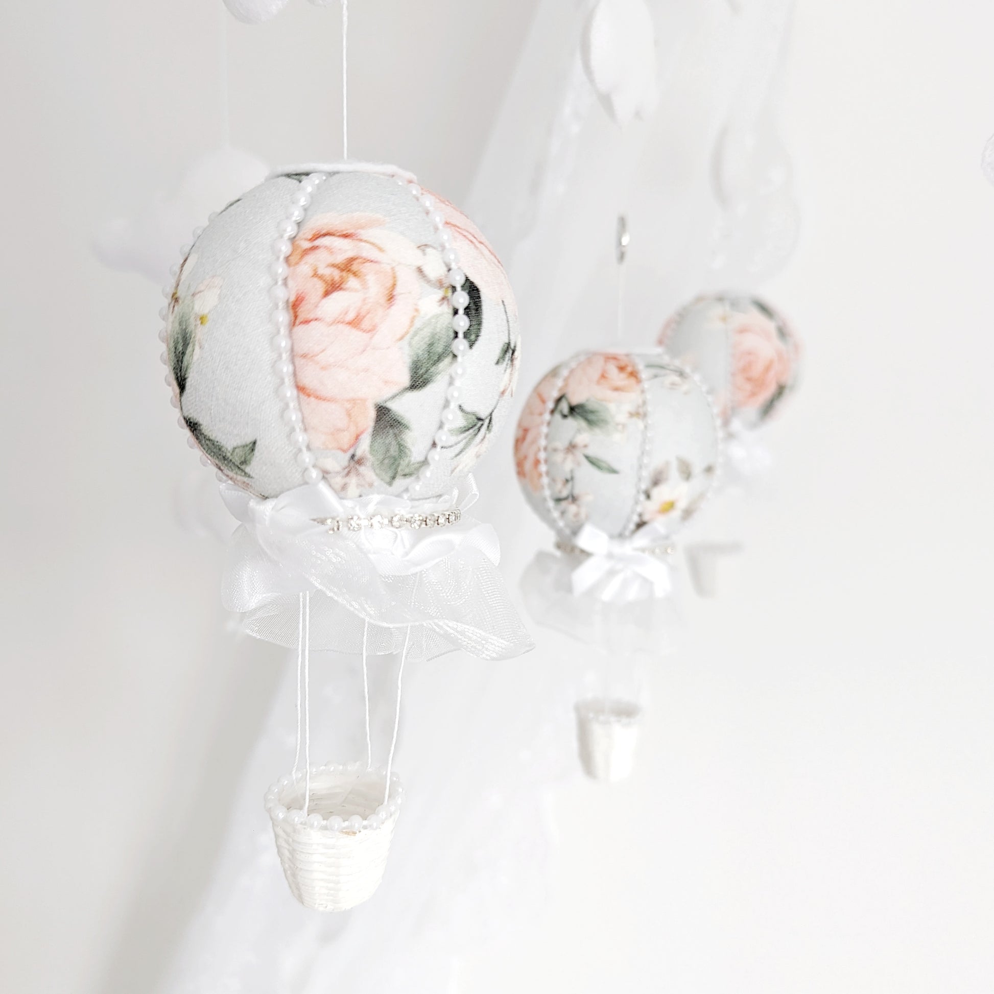 Close-up of a blush floral hot air balloon with lace and ribbon detailing on a handmade baby mobile.