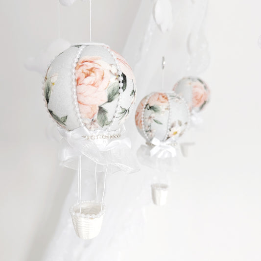 Close-up of a blush floral hot air balloon with lace and ribbon detailing on a handmade baby mobile.