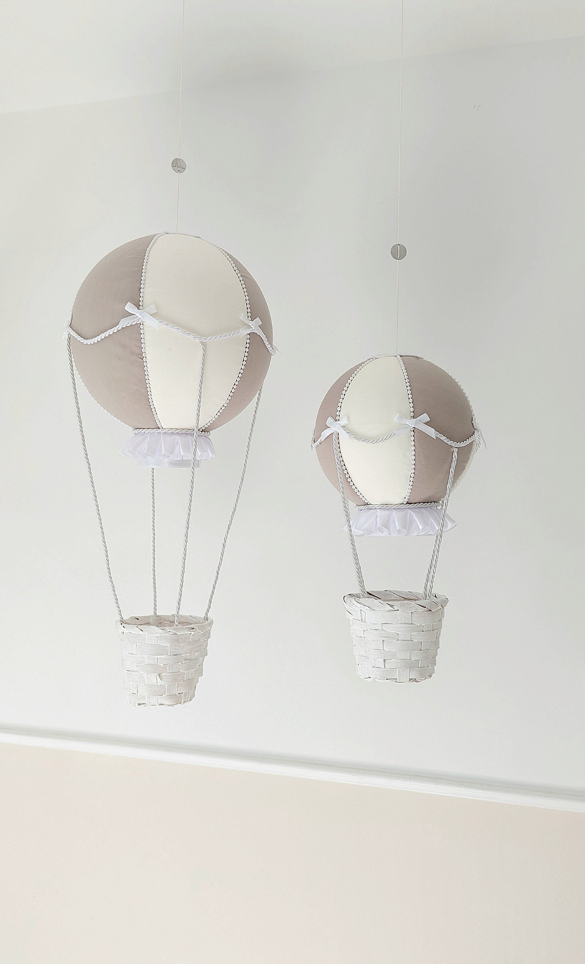 A set of handcrafted nursery balloons in neutral tones, trimmed with bows and ready to drift into little daydreams.