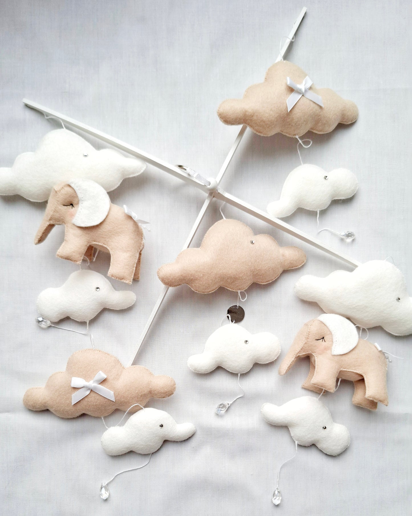 Flat lay of stitched elephants and cloud pieces in soft beige and white, ready to become a timeless nursery mobile.
