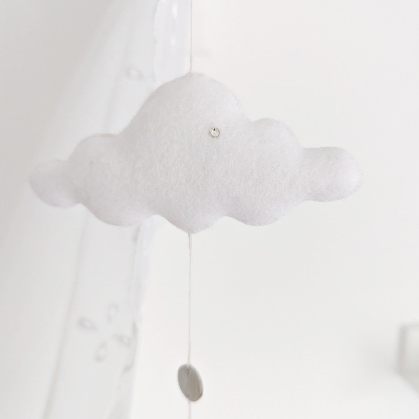 Delicate single-drop baby mobile with a handcrafted hot air balloon and floating white cloud, captured in soft lighting.