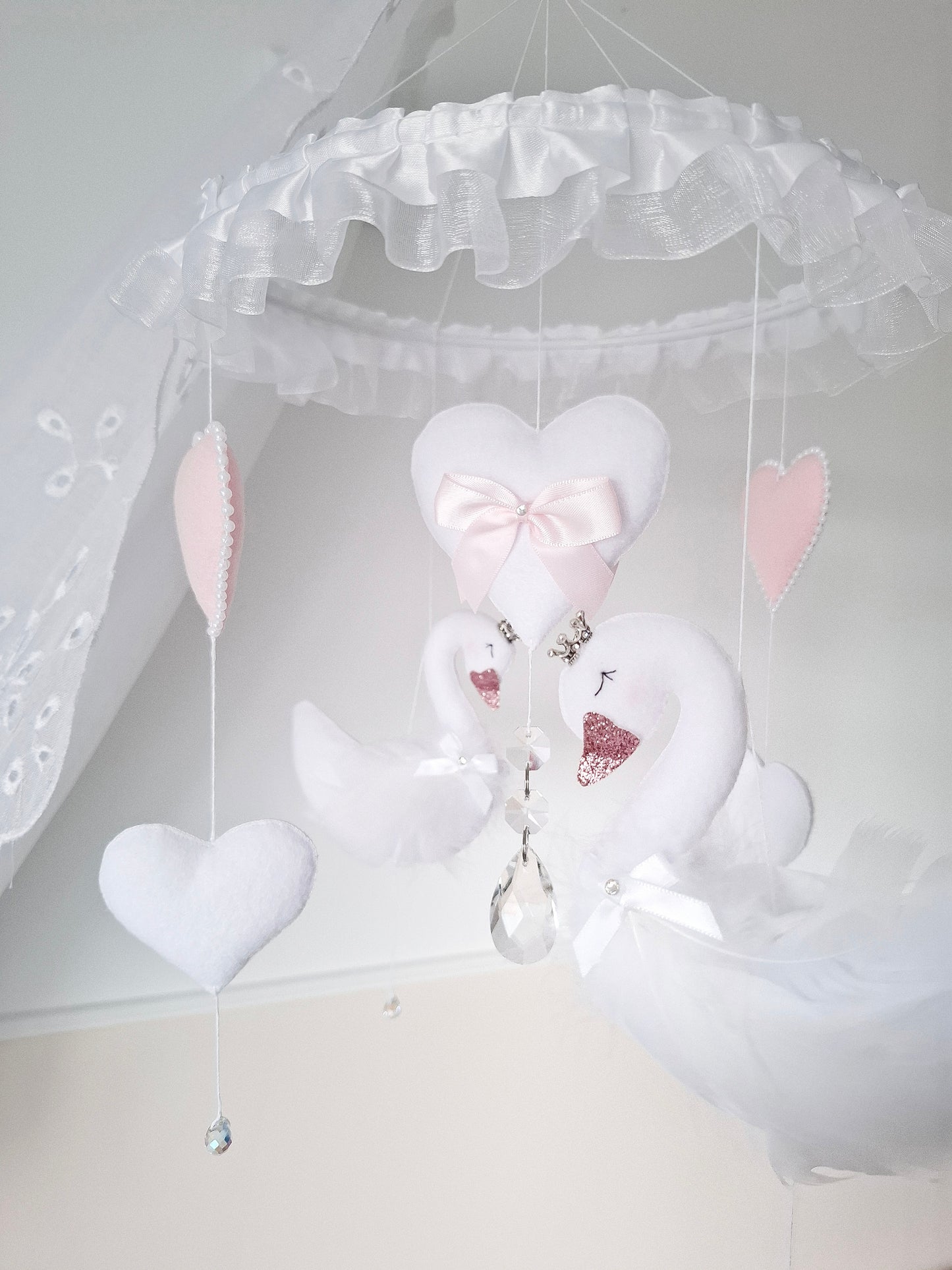 Side view of handmade swan baby mobile with hearts and crystals,elegant nursery decor in gentle pink and white.