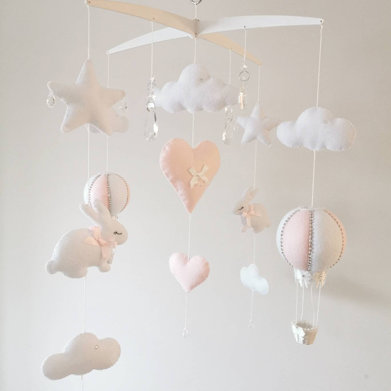 Artisan felt mobile with delicate pink bunny, cloud, and hot air balloon details—perfect for a baby girl's room.