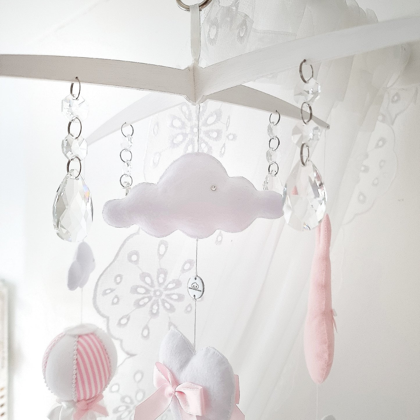 Close-up of soft pink bunnies with bow on a handmade baby girl mobile with heart and cloud details.