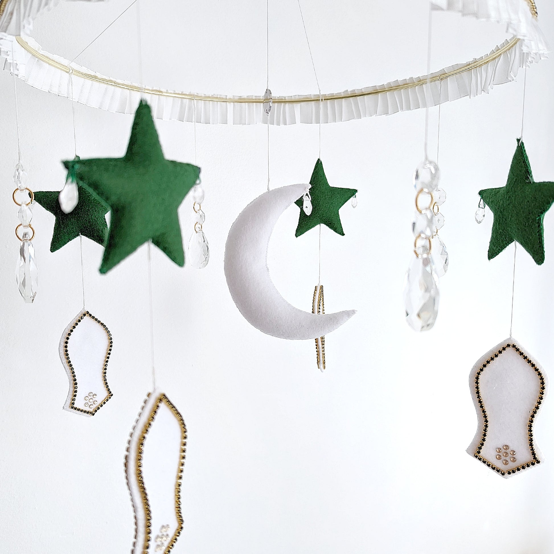 Crescent moon mobile with green stars, mosque shapes, and a felt sandal detail symbolising the Prophet Muhammad’s (pbuh) footsteps.