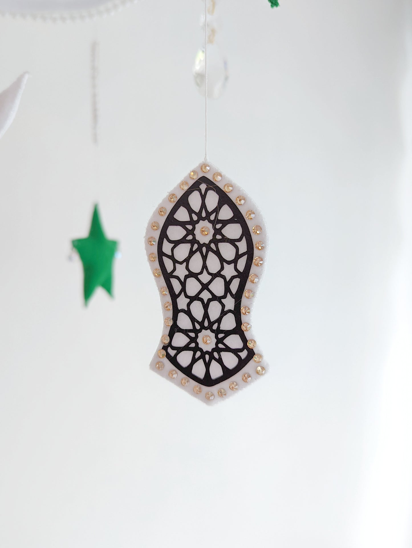 Crescent moon baby mobile featuring deep green stars and intricate sandal symbols, inspired by Islamic tradition.