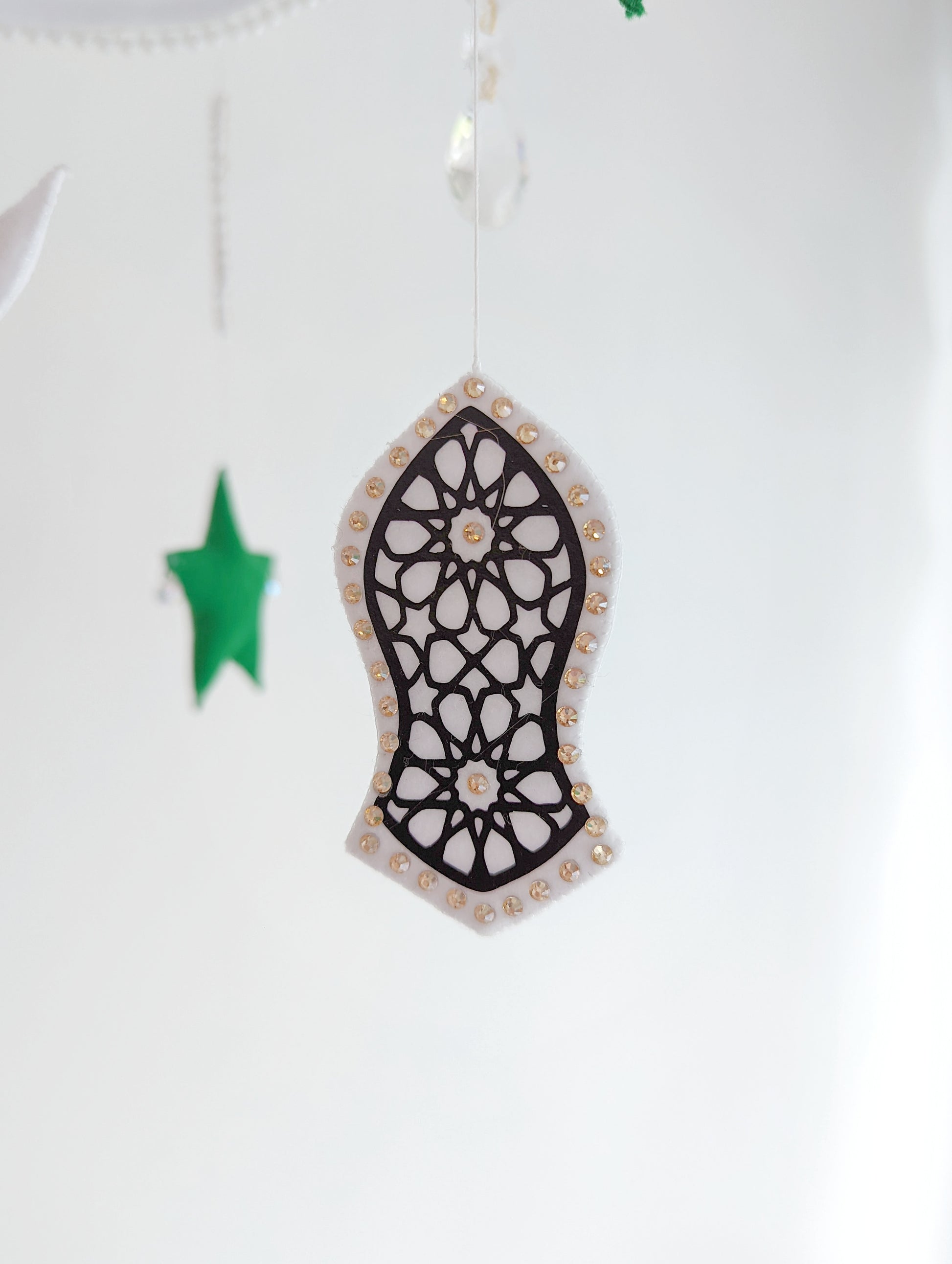 Crescent moon baby mobile featuring deep green stars and intricate sandal symbols, inspired by Islamic tradition.