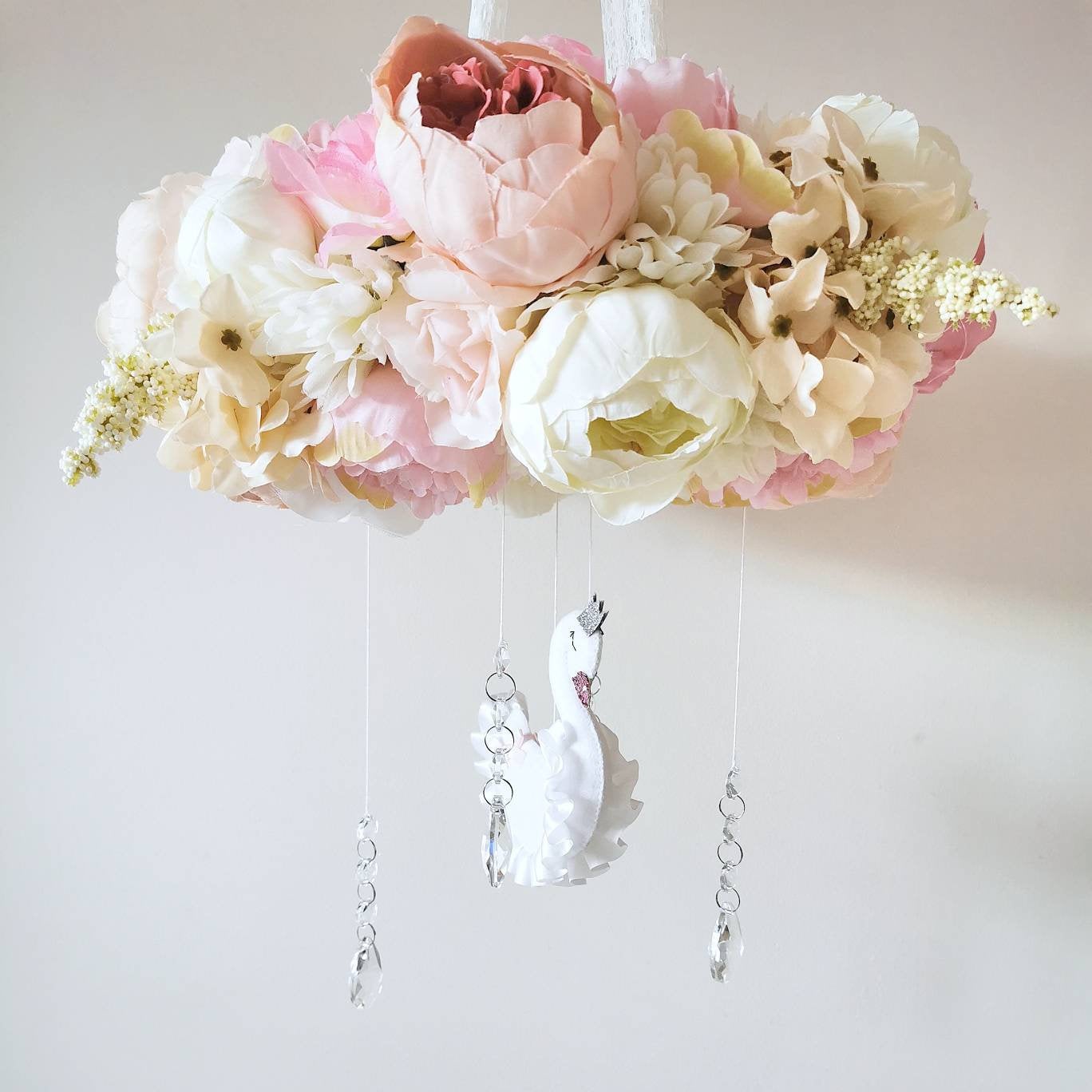 Crystals and soft layers catch the light beneath a crown of flowers and a swan bringing an ethereal glow to this mobile