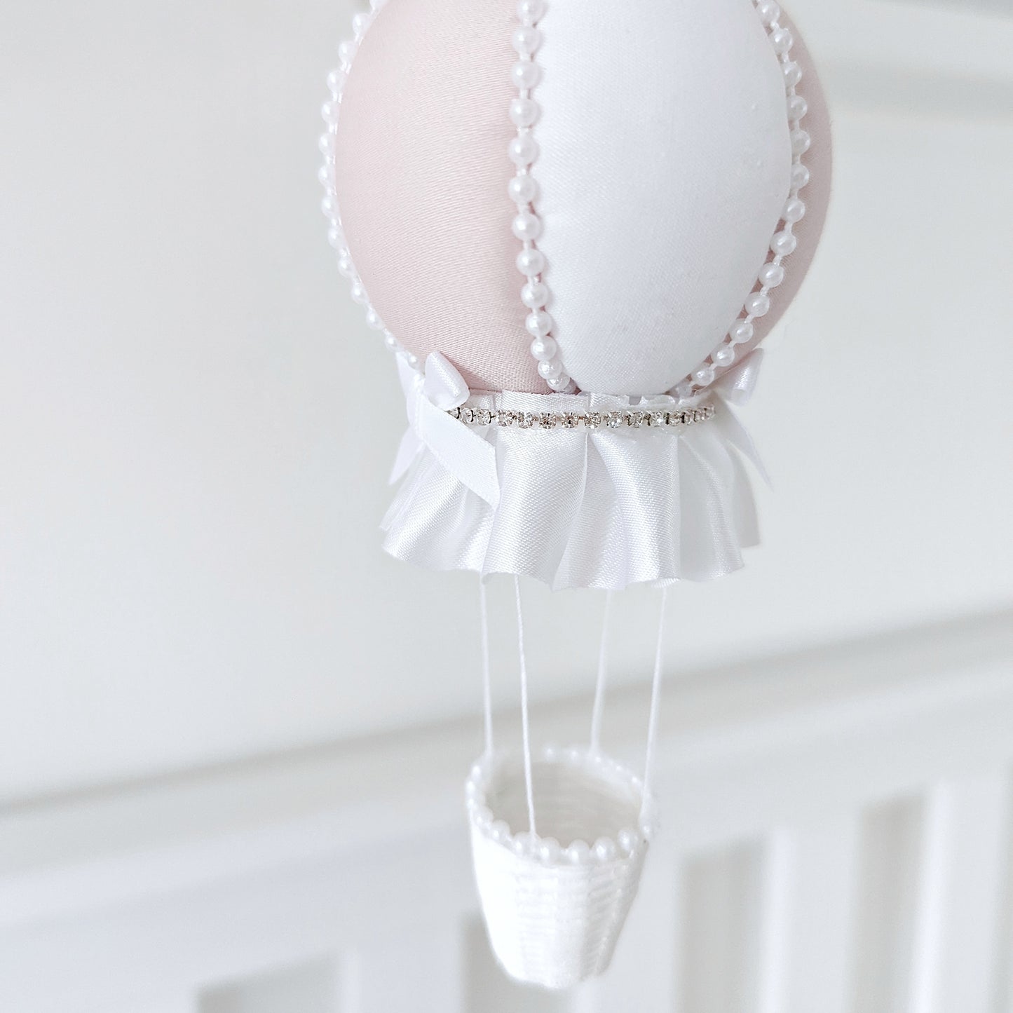 Elegant nursery mobile with cascading crystals, ivory roses, and a handmade balloon in soft pink and white.