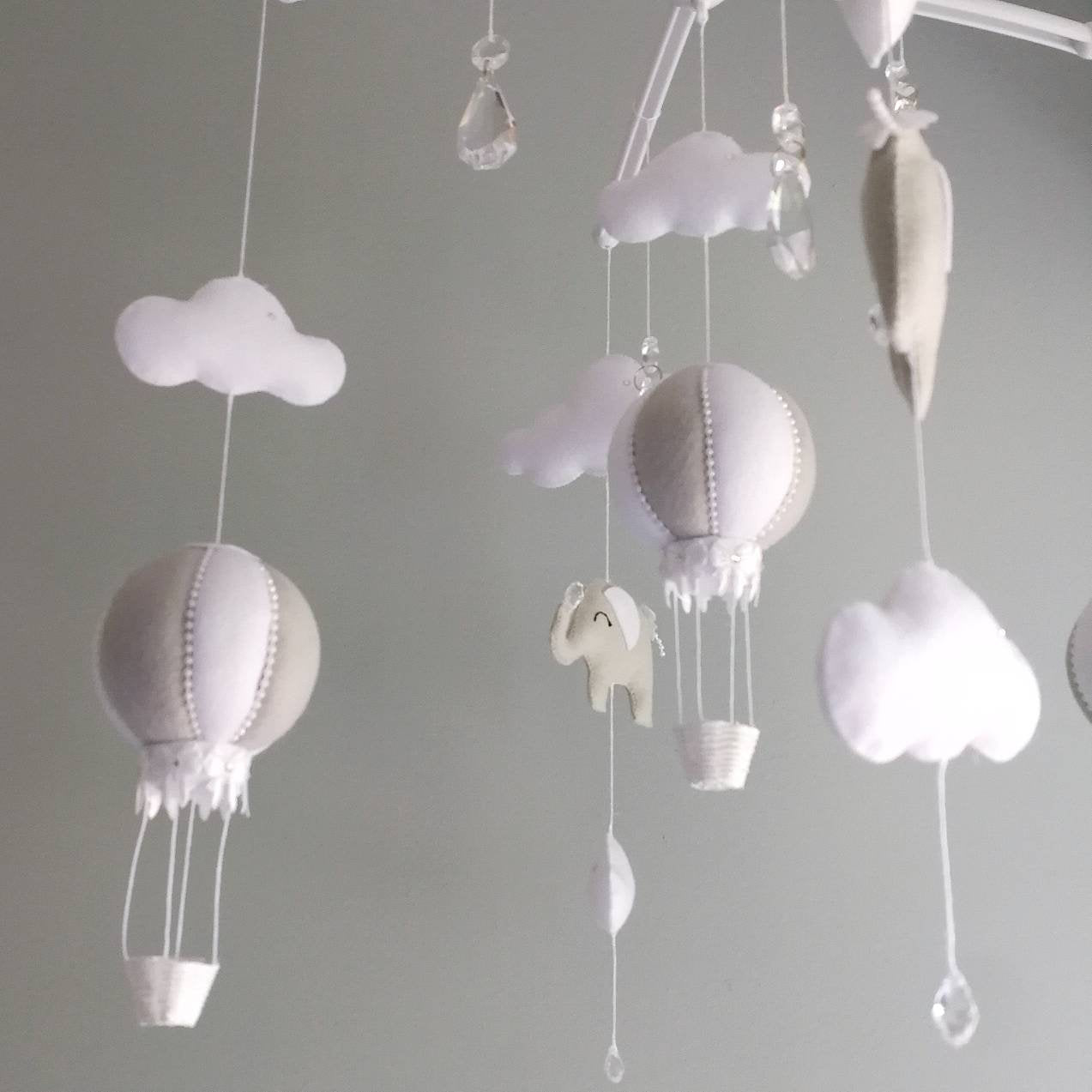 Close-up of a softly stitched felt hot air balloon in light grey and white, bringing quiet wonder to a handcrafted nursery mobile.