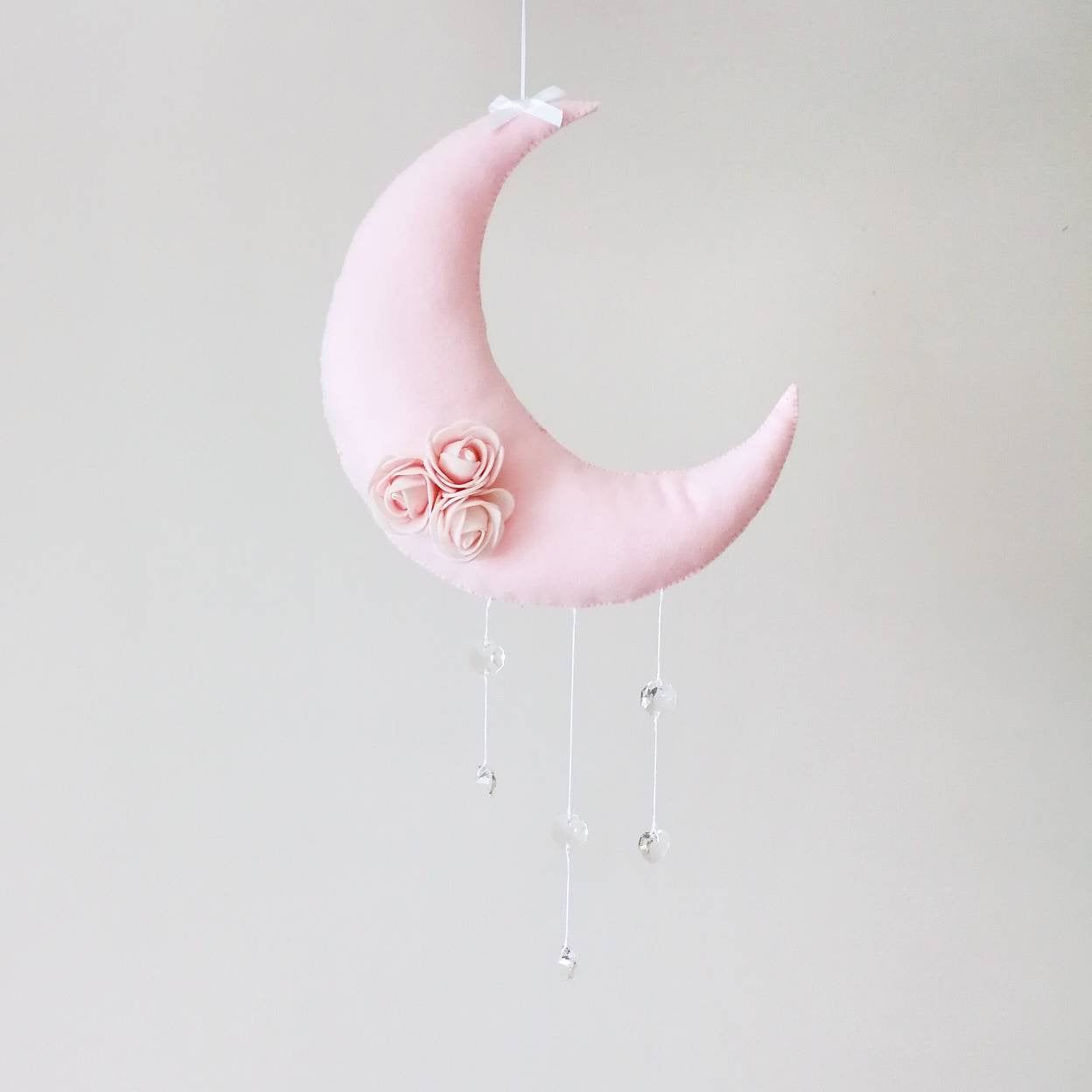 Close-up of blush pink felt moon with handcrafted floral detail bringing a soft poetic feel to nursery or children’s wall decor