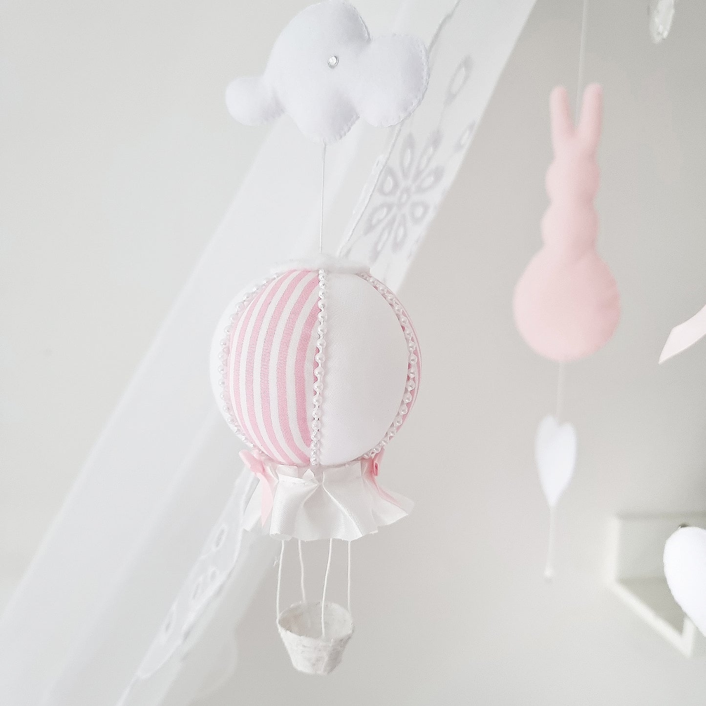 Handcrafted nursery mobile featuring pastel pink bunnies, soft hearts, and a striped hot air balloon—perfect for a baby girl nursery
