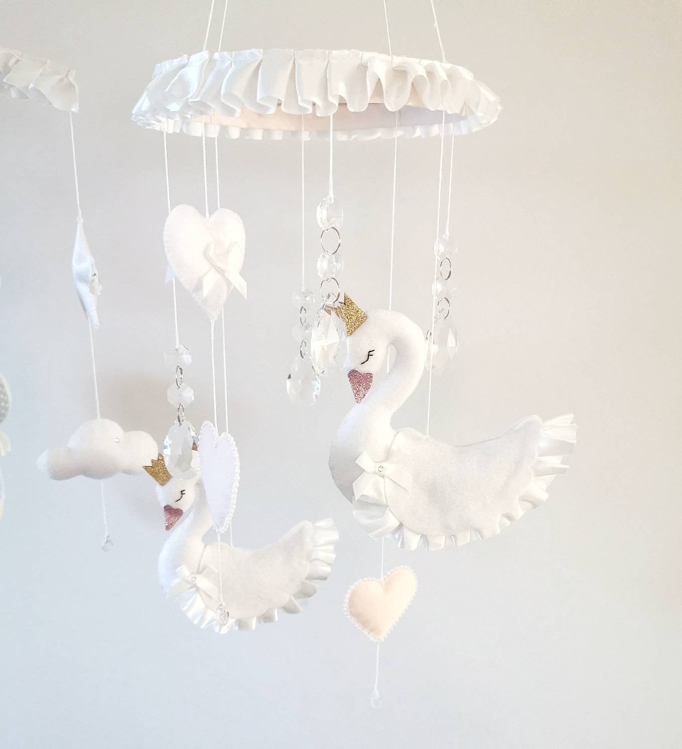 Handcrafted felt swan mobile in white and pink with romantic, whimsical details and soft textures.