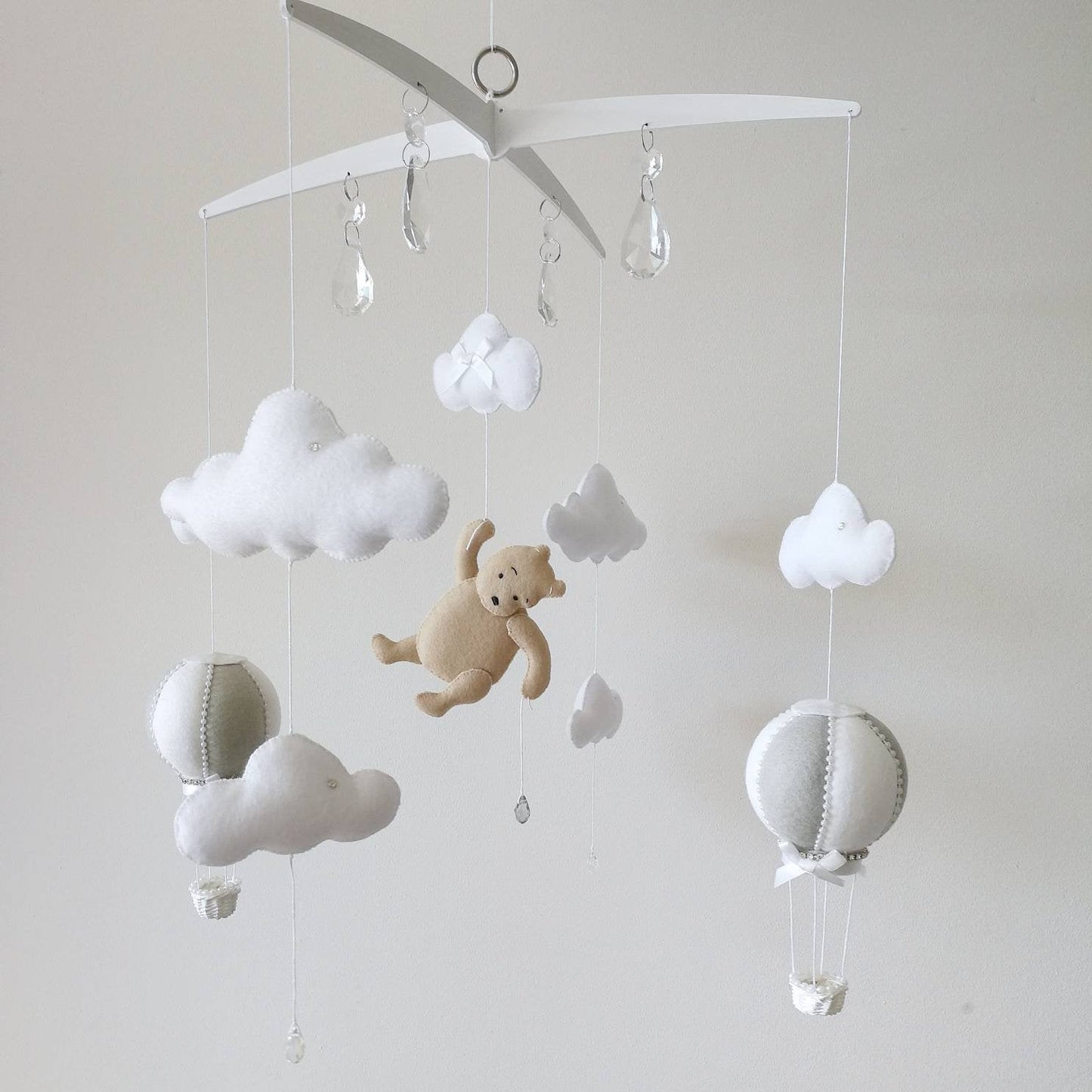 Neutral tones and soft textures create a calming scene where a little bear floats gently above a peaceful baby room