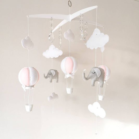 Handmade baby mobile in pink and white with gentle felt elephants and clouds designed to float softly in a dreamy nursery space