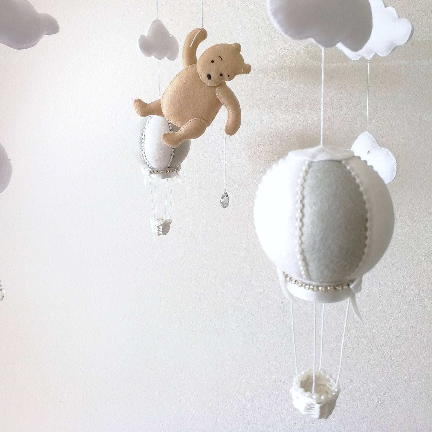 Light grey and white hot air balloons with crystal raindrops add a touch of quiet magic to this handmade nursery mobile