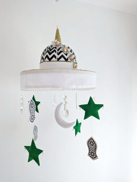 Islamic nursery mobile with green stars, crescent moon, and symbolic Sandal of the Prophet Muhammad (pbuh), set beneath a bold mosque dome.
