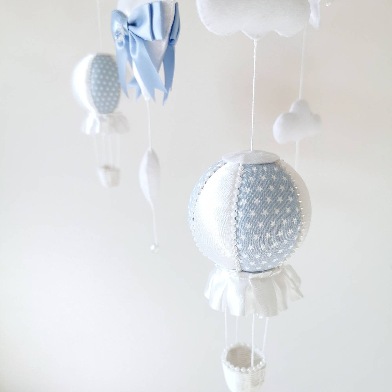 Close up of soft blue and white balloons from a luxury baby boy mobile with gentle details.