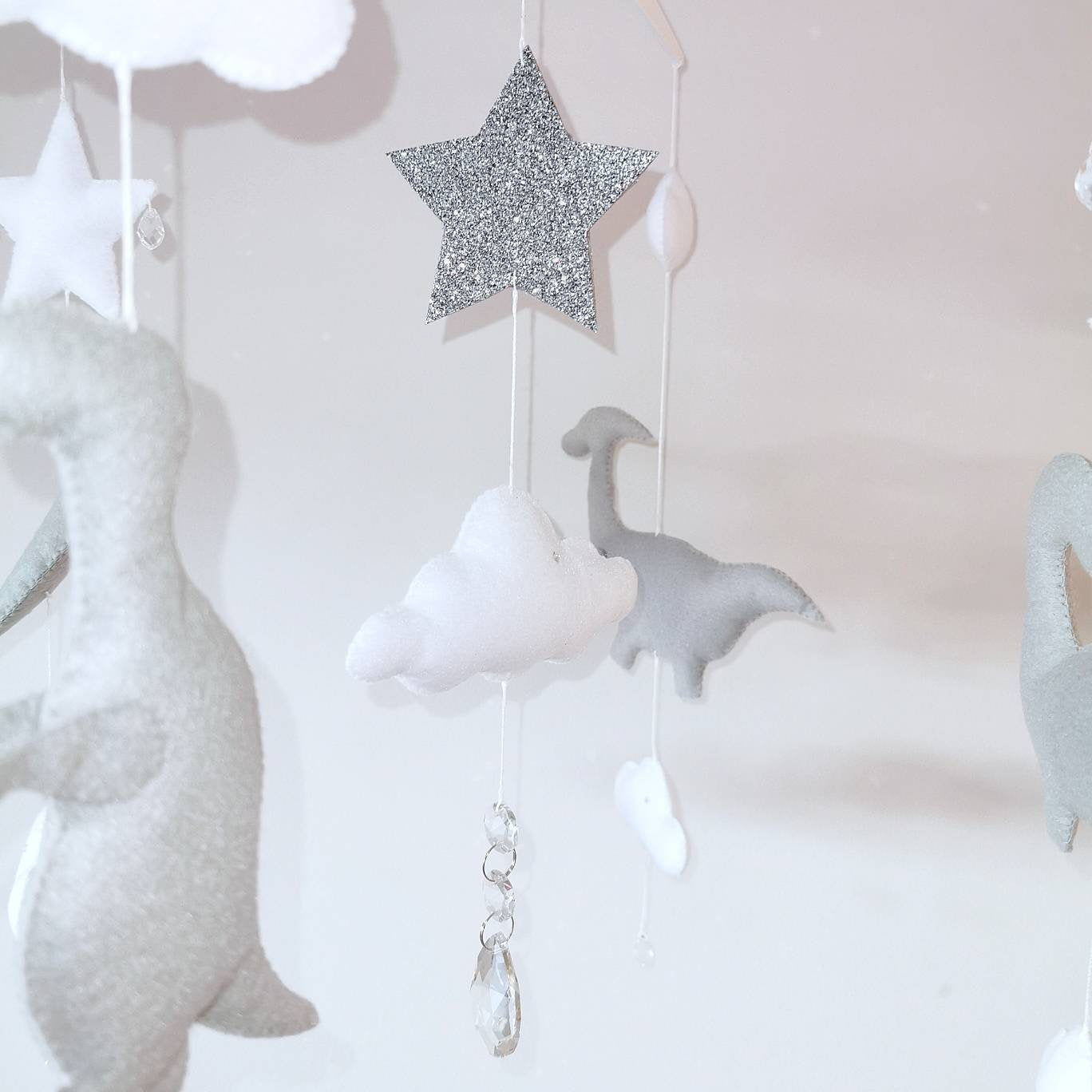 Luxury felt mobile with gentle clouds, sparkling star, and handcrafted dinosaurs floating in a dreamy scene.