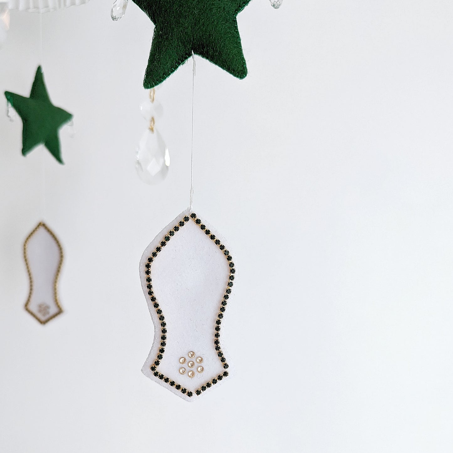 Luxury Islamic baby mobile with embroidered mosque motifs, a crescent moon, and a respectful sandal symbol honouring the Prophet Muhammad (pbuh).