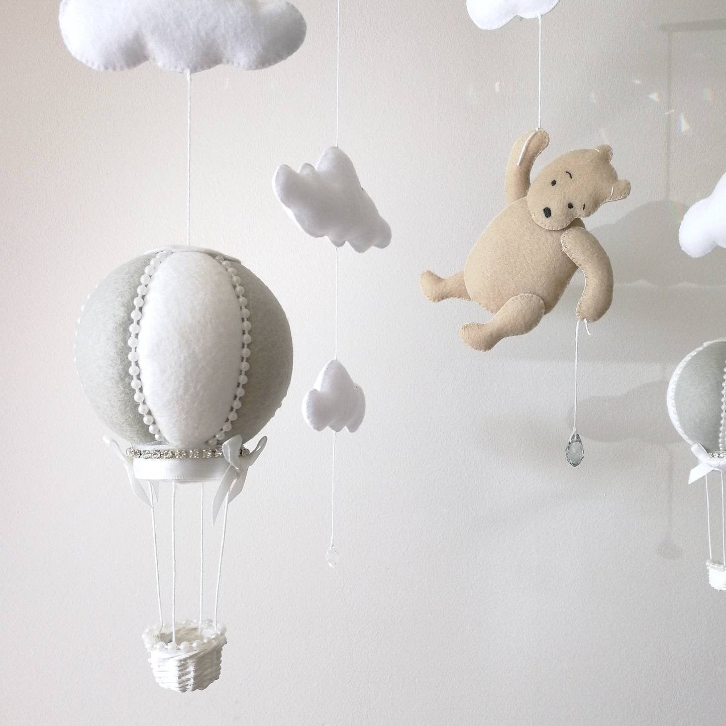 White felt clouds and delicate crystal drops bring light and softness to a lovingly handcrafted baby mobile