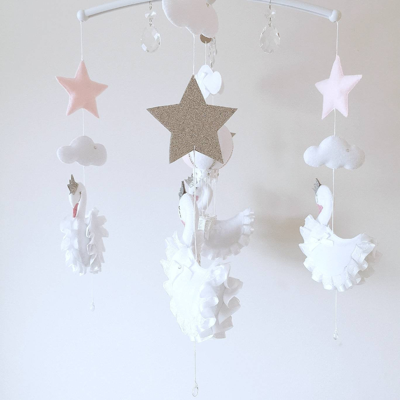 Sparkling stars and soft clouds float quietly above, adding a little stardust to this elegant handmade nursery mobile