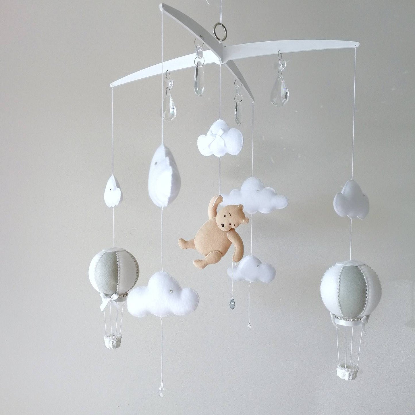 Handmade baby mobile with a soft honey bear floating among clouds and hot air balloons bringing a warm storybook charm to the nursery