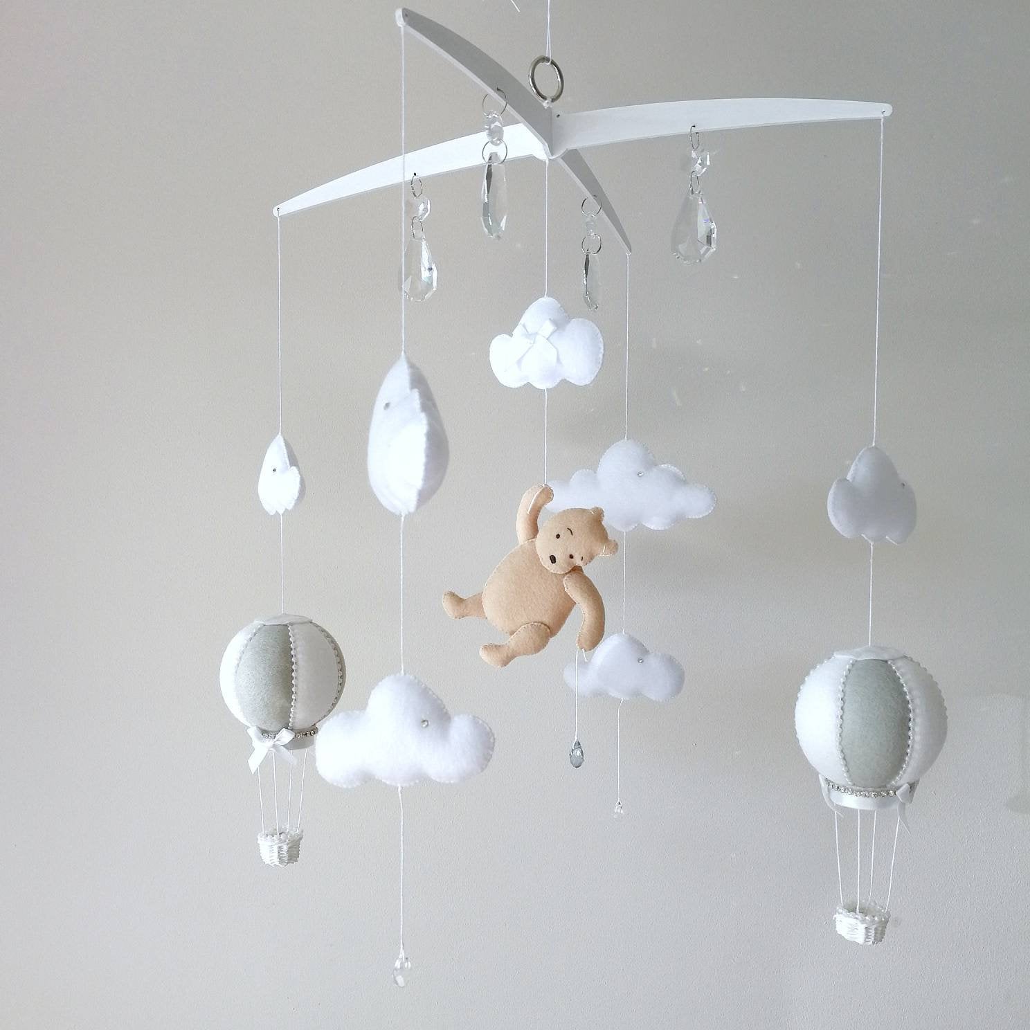 Handmade baby mobile with a soft honey bear  floating among clouds and hot air balloons bringing a warm storybook charm to the nursery