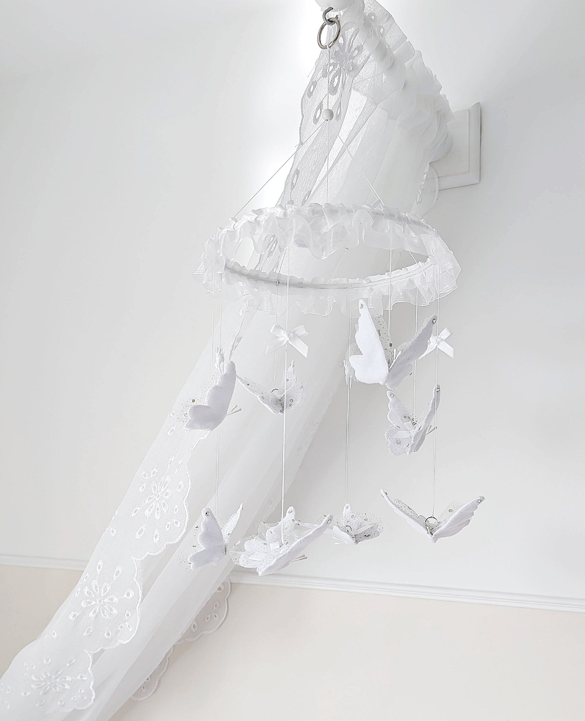 Angelic white butterfly mobile with lace-edged wings, perfect for a light-filled baby nursery or a gentle remembrance space.
