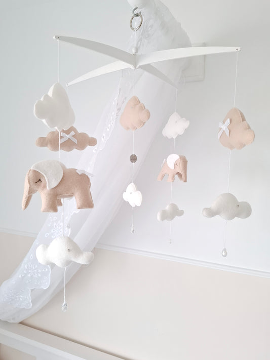 Soft neutral baby mobile with beige and white felt elephants, white clouds, and crystal drops, suspended from an exclusive cross-style hanger.