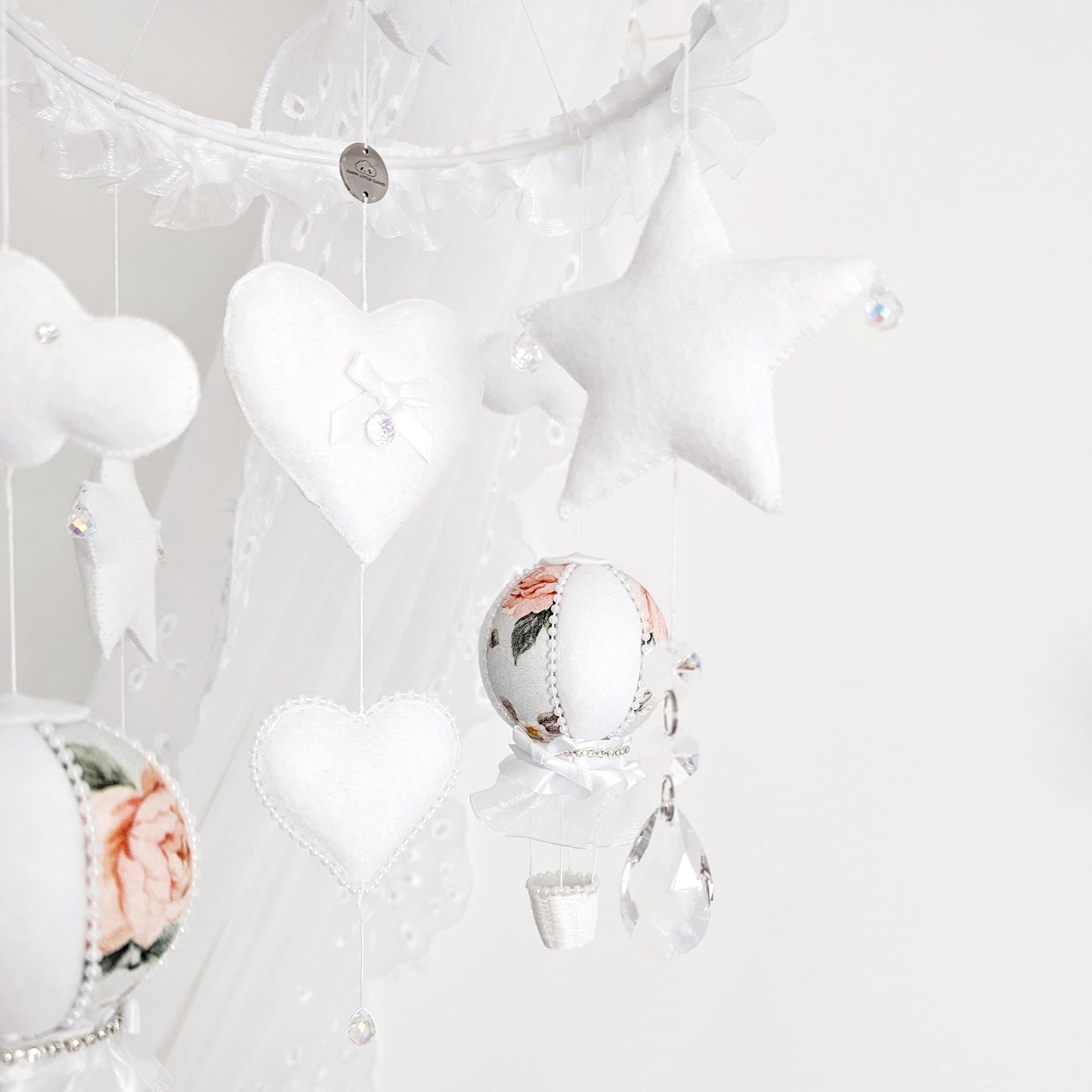 Blush floral hot air balloons with stars and crystal accents, floating from a ruffled round hanger—perfect for a dreamy baby space.