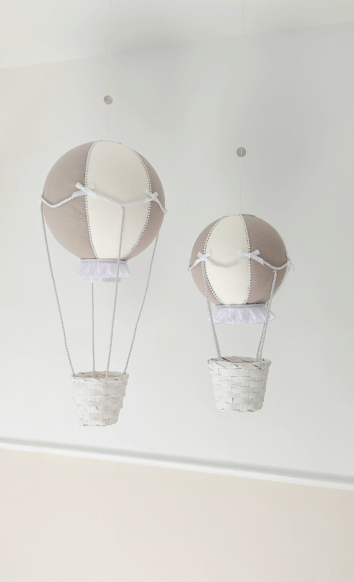 A set of handcrafted nursery balloons in neutral tones, trimmed with bows and ready to drift into little daydreams.