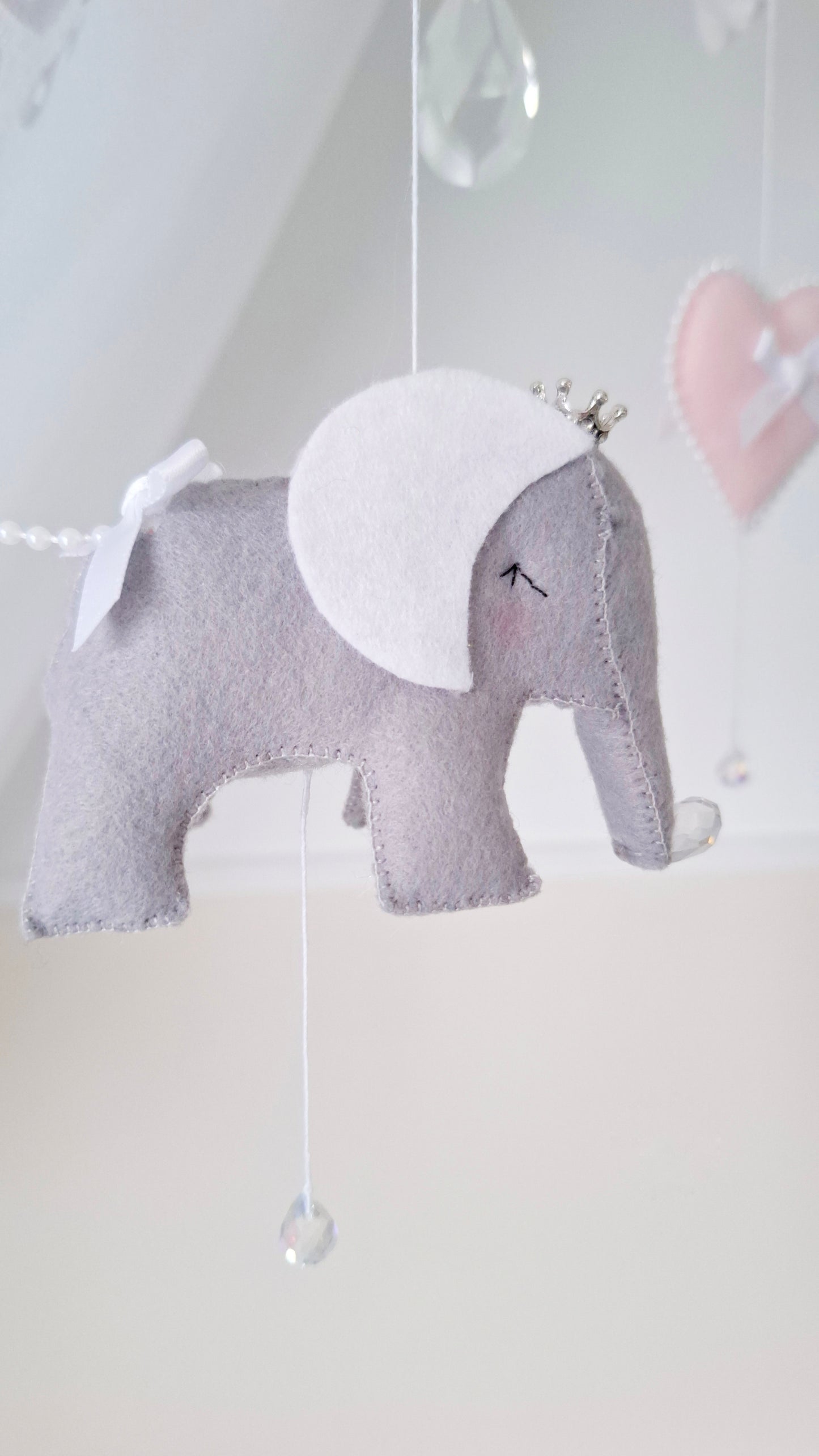 Felt elephant baby mobile featuring white bows, shimmering crystals, and sweet pastel pink hearts.