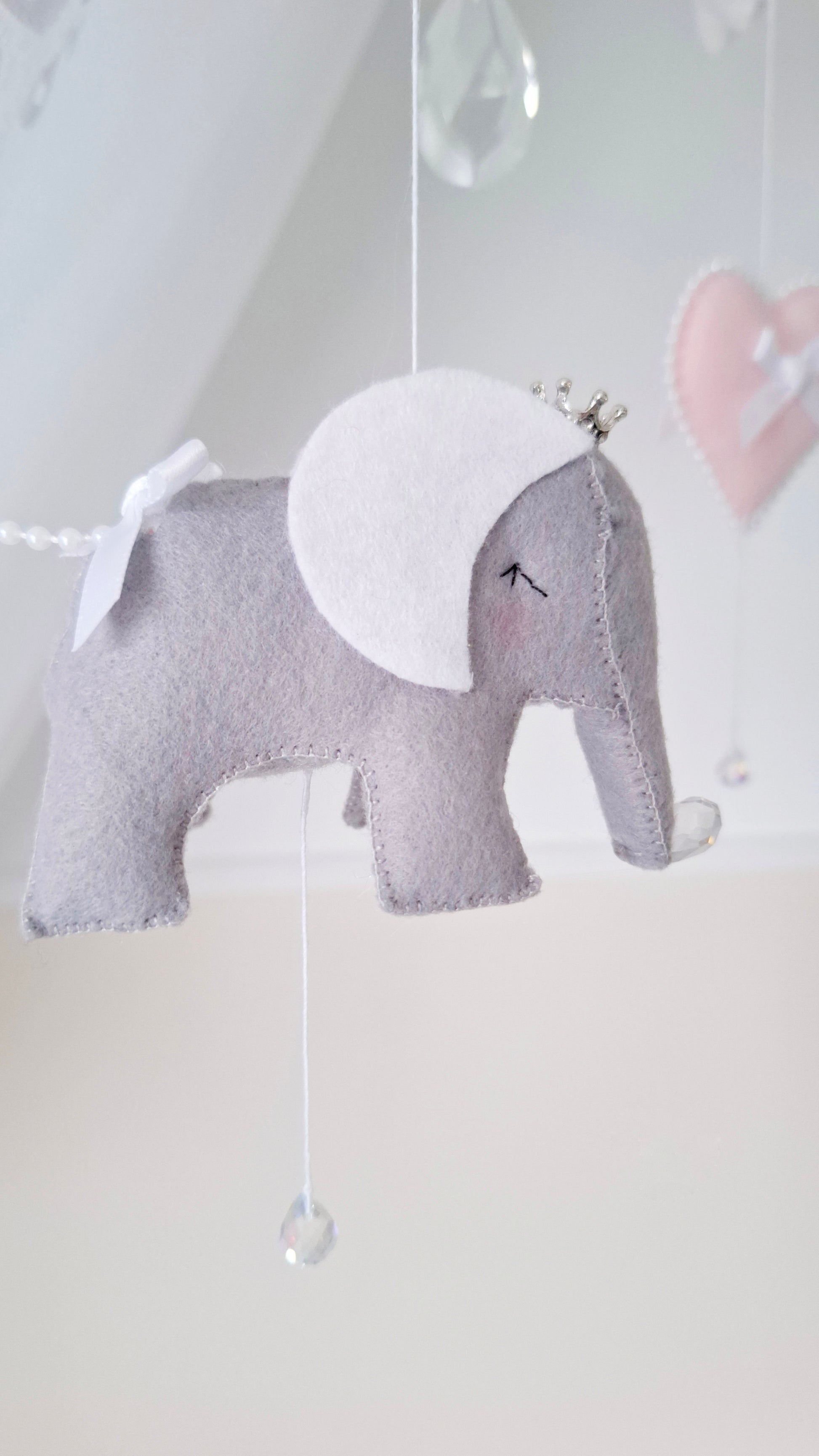 Felt elephant baby mobile featuring white bows, shimmering crystals, and sweet pastel pink hearts.