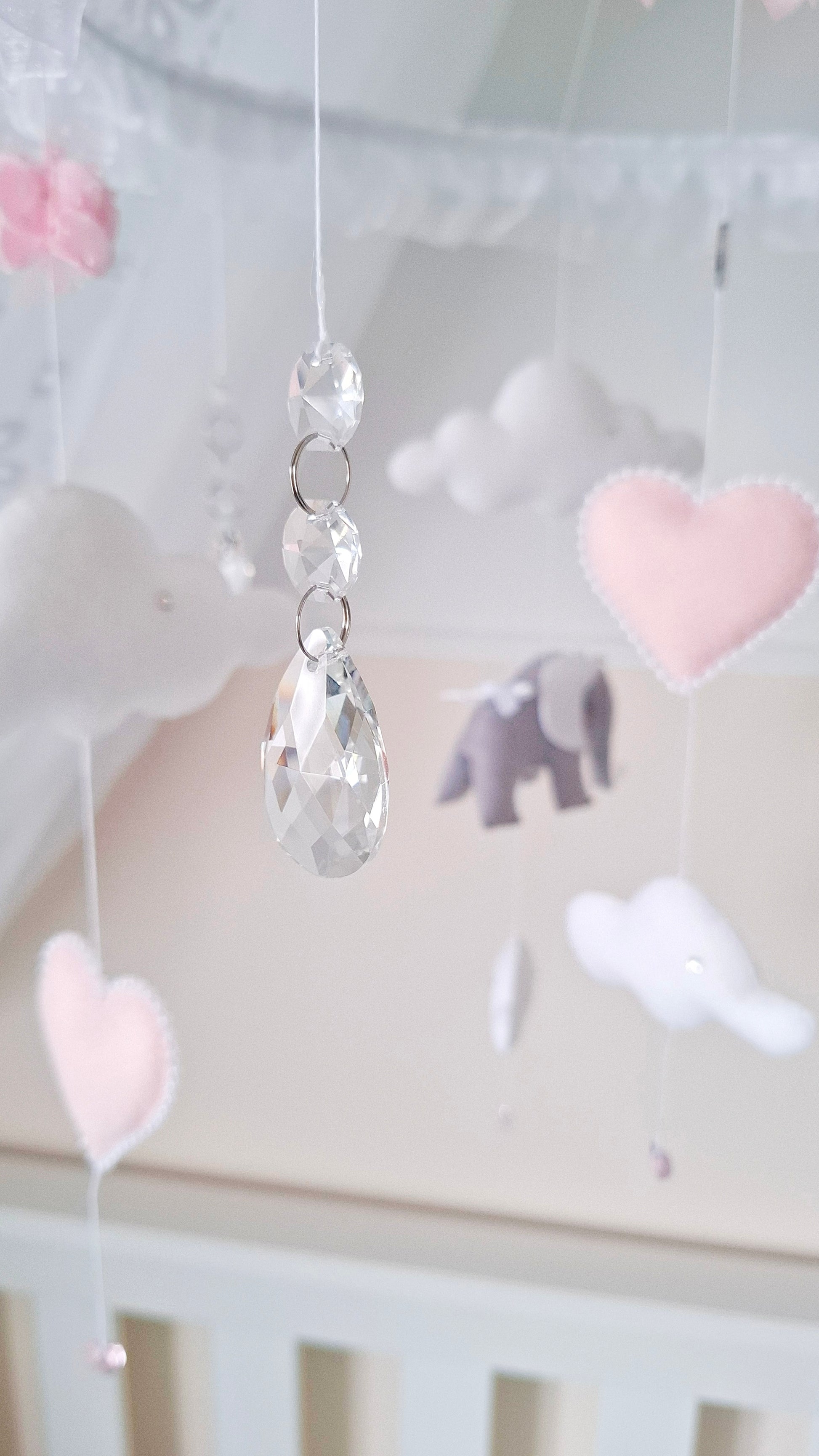 High-end baby mobile with dreamy clouds, tiara-topped elephants, and romantic pink heart details for elegant nurseries.

