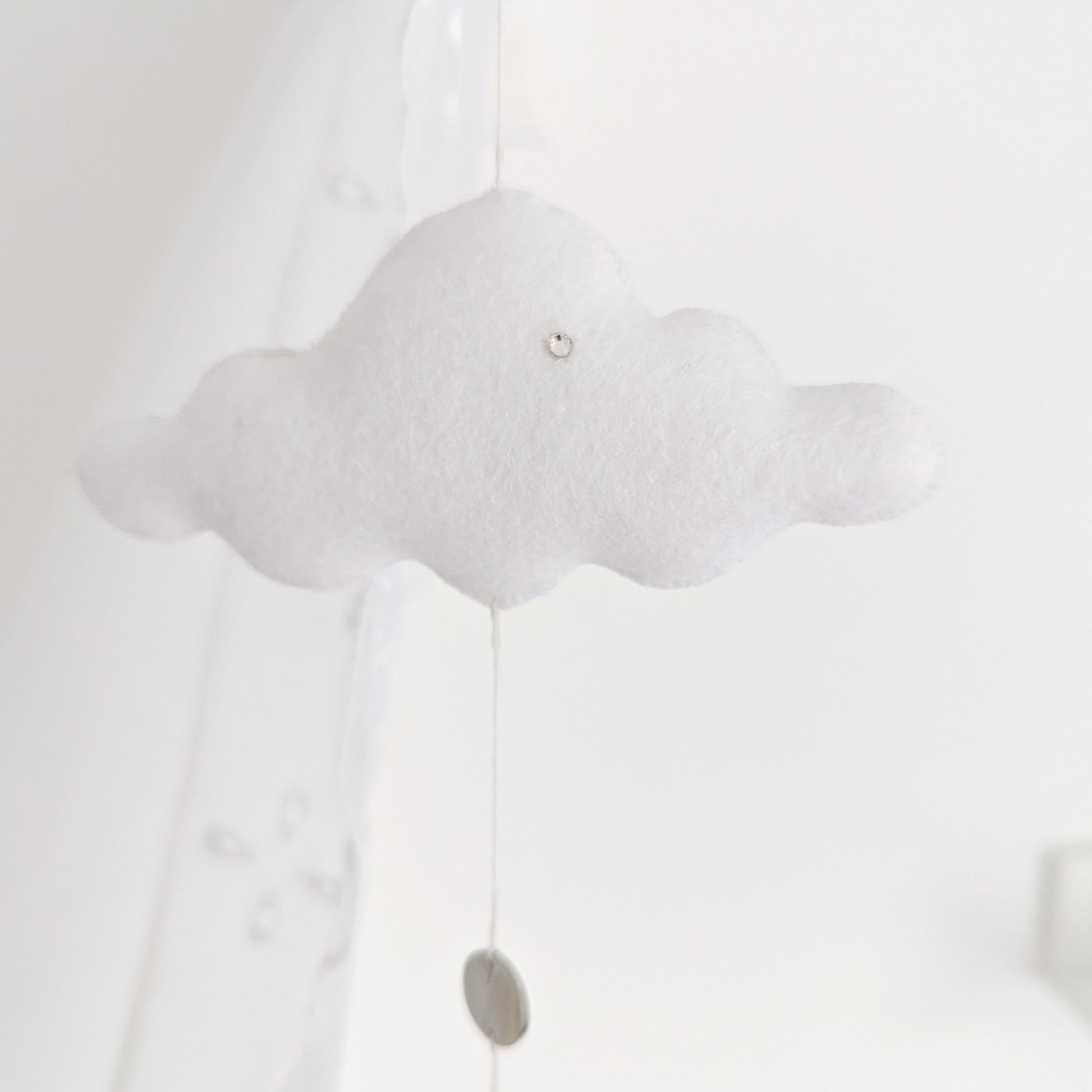 Delicate single-drop baby mobile with a handcrafted hot air balloon and floating white cloud, captured in soft lighting.

