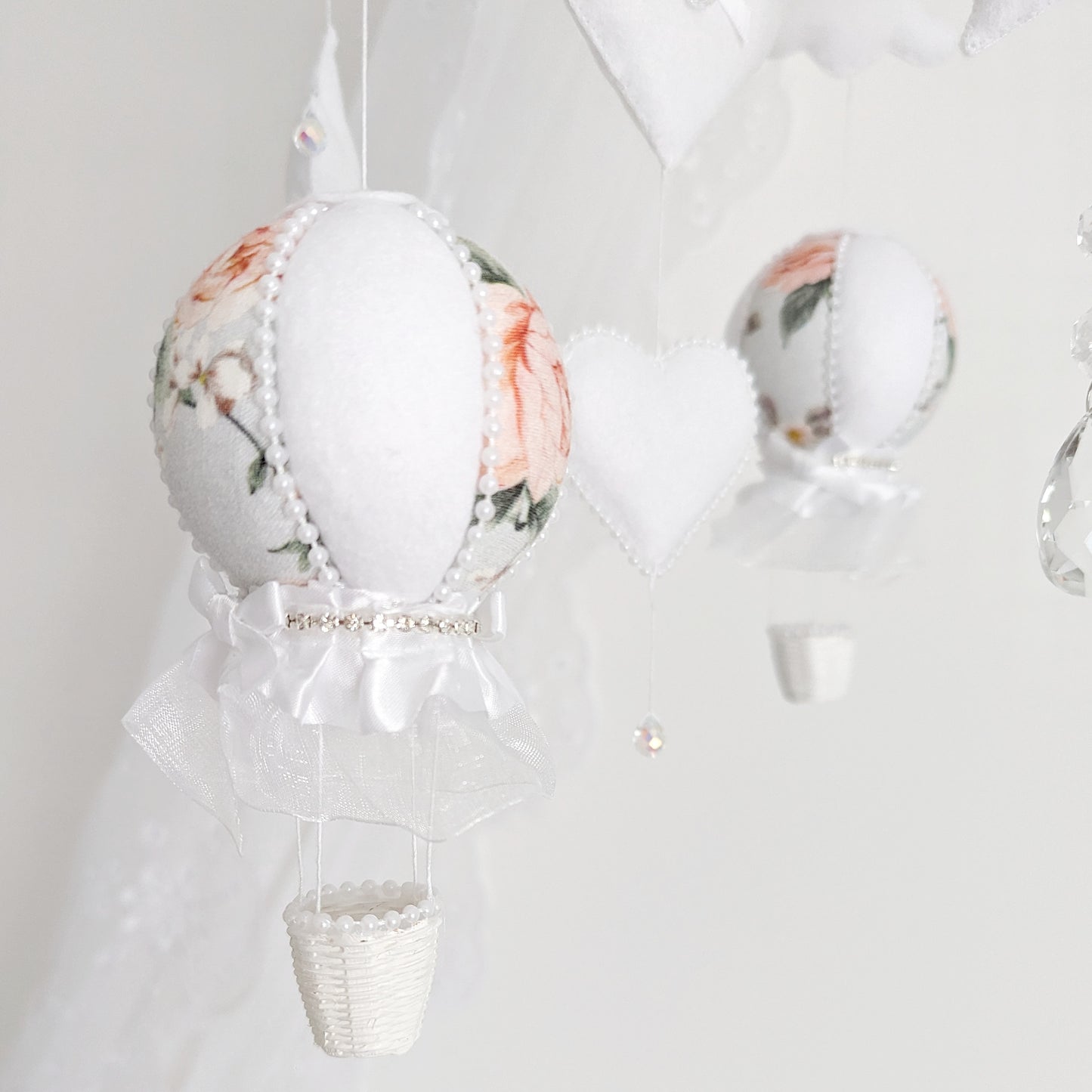 Close-up of floral balloon, felt star, and crystal drop—elegant details on a luxury handmade baby mobile.