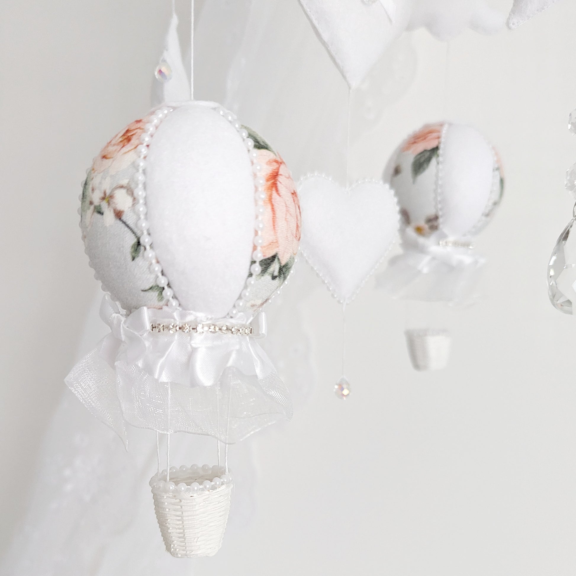 Close-up of floral balloon, felt star, and crystal drop—elegant details on a luxury handmade baby mobile.