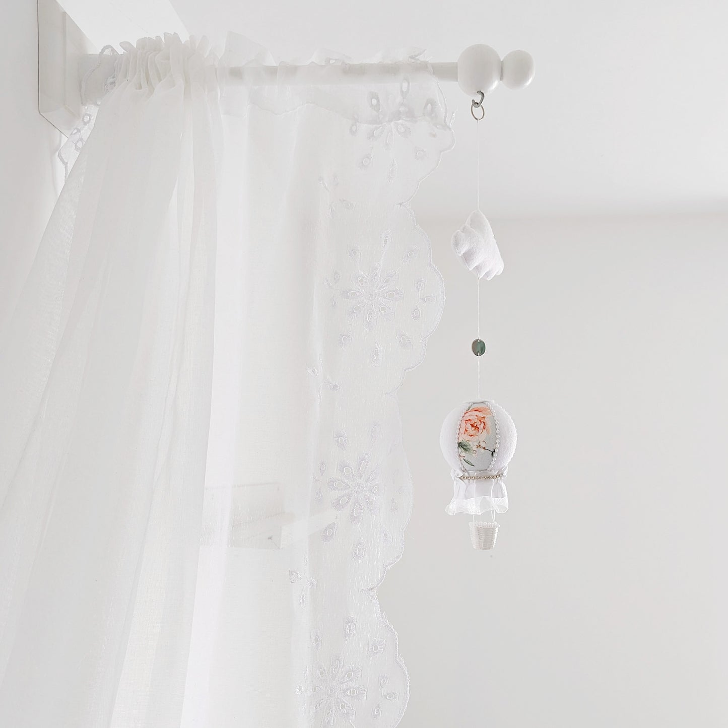 Elegant baby mobile with a single floral hot air balloon and white felt cloud, styled against a lace canopy.