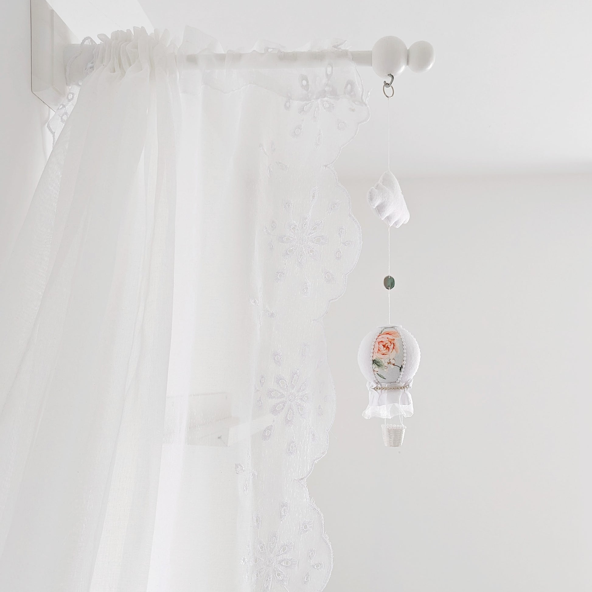 Elegant baby mobile with a single floral hot air balloon and white felt cloud, styled against a lace canopy.