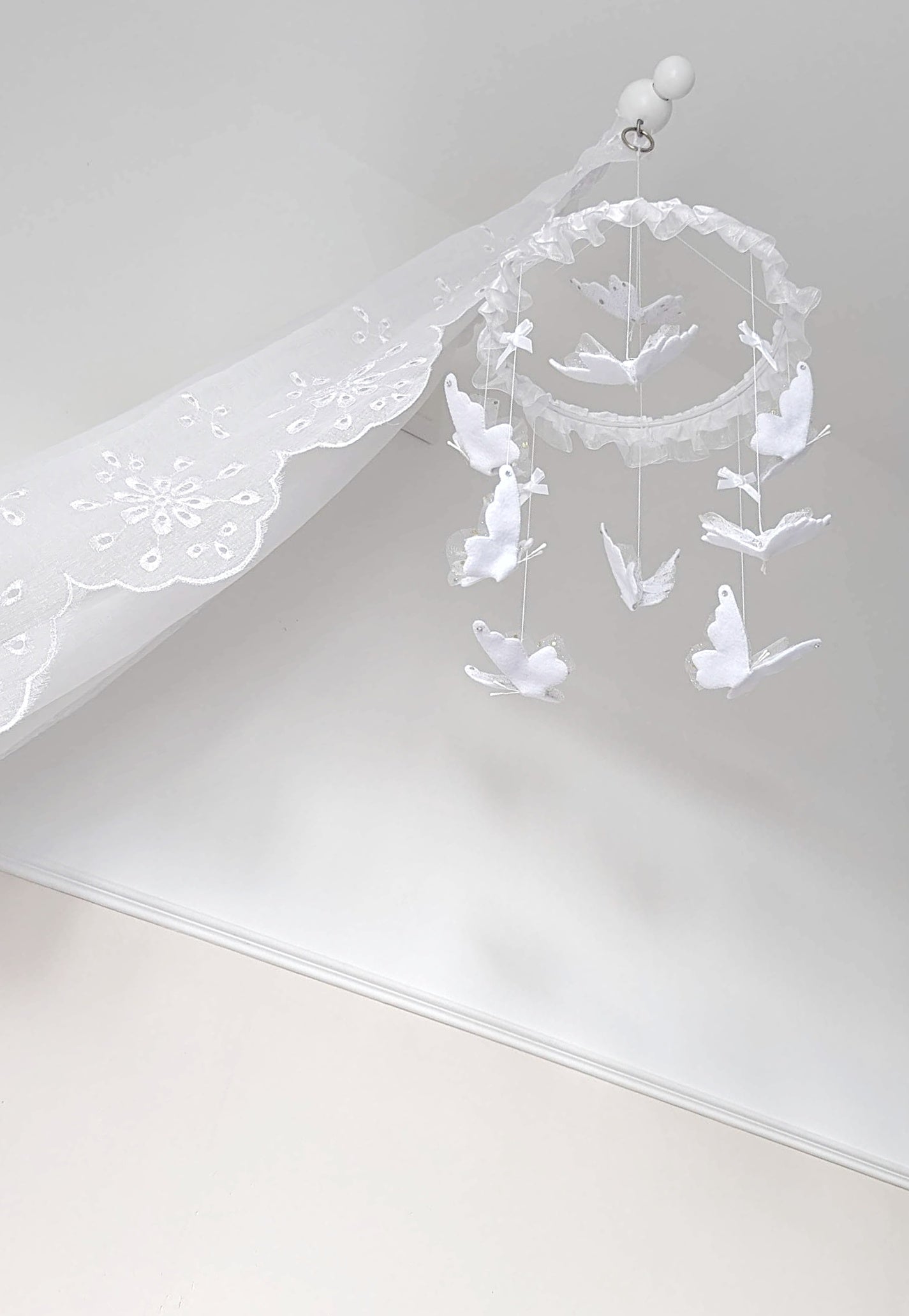 Delicate butterfly baby mobile in all white, handcrafted with soft lace wings and ruffled trim for a pure, peaceful nursery.

