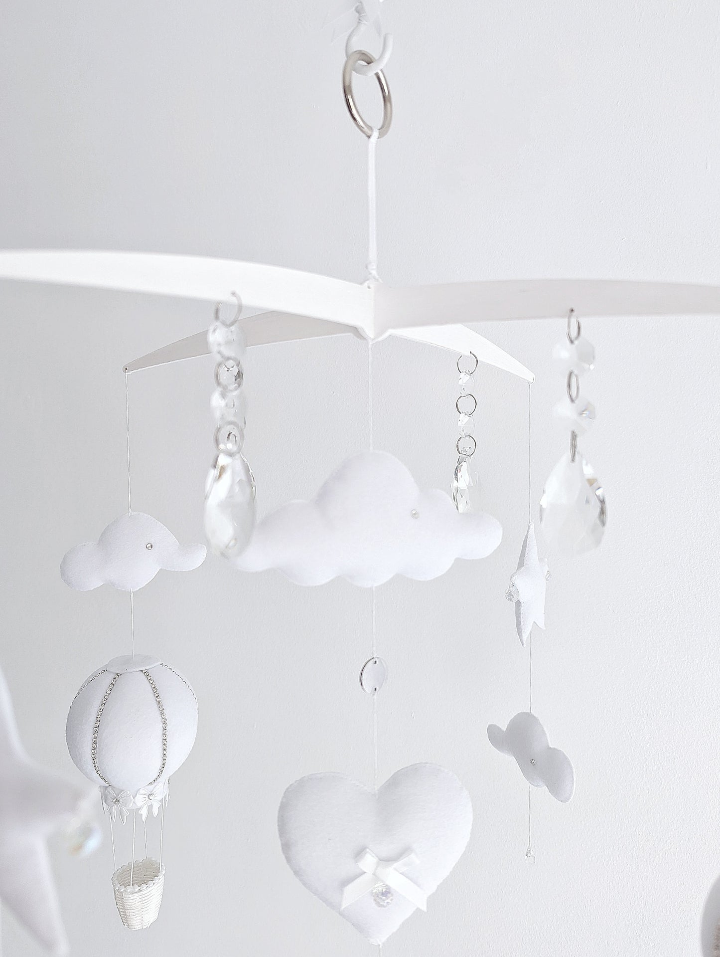 Delicate handmade baby mobile with white hot air balloons, fluffy clouds, and dreamy sky elements for a modern luxury nursery.

