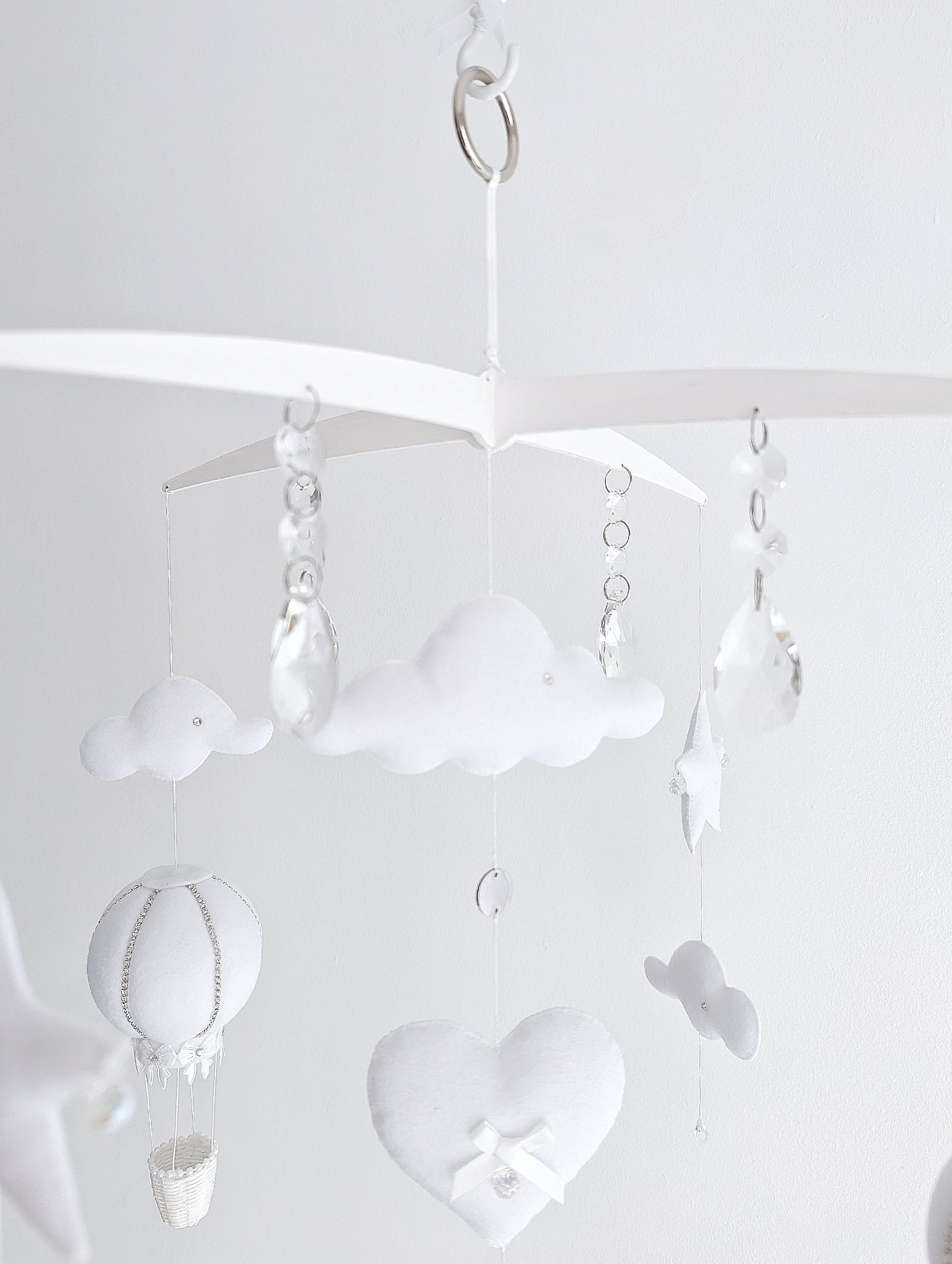 Delicate handmade baby mobile with white hot air balloons, fluffy clouds, and dreamy sky elements for a modern luxury nursery.

