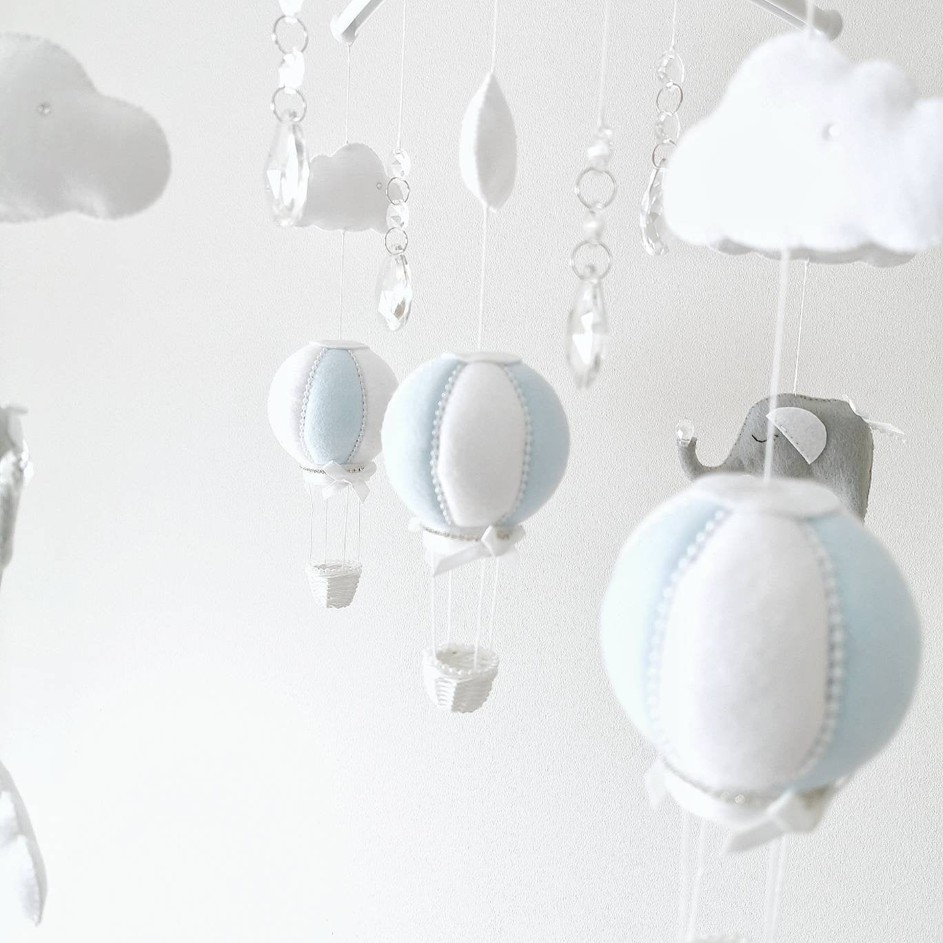 A floating mobile of blue balloons and sleepy elephants among soft clouds perfect for creating a peaceful nursery atmosphere

