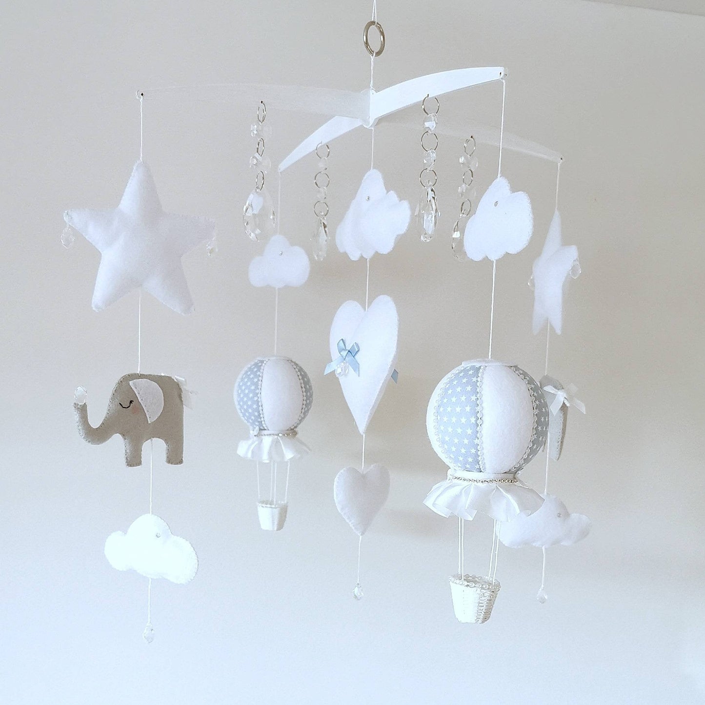 Close up of soft blue and white hot air balloons with delicate stitching, clouds, stars and  waving elephant below.