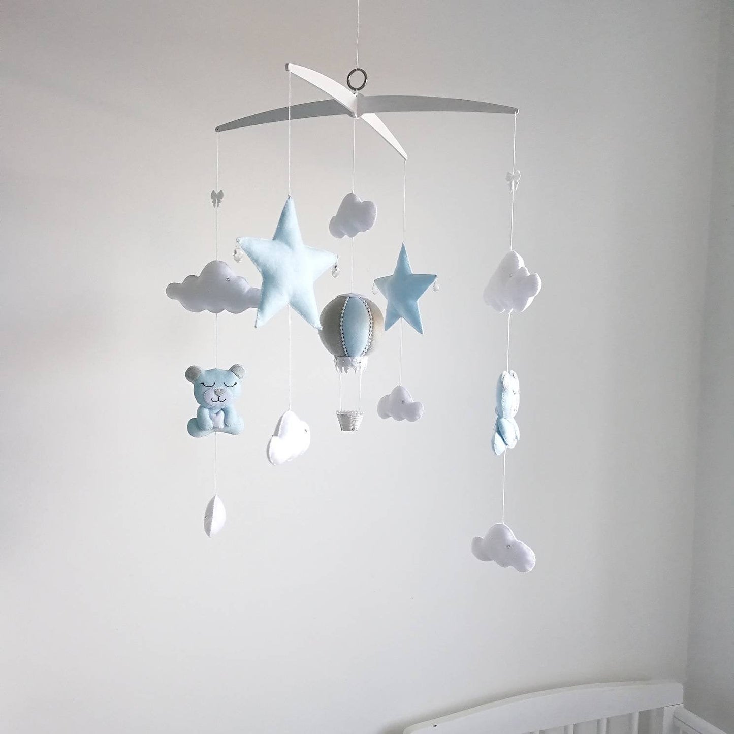 Handmade baby mobile with blue stars, white clouds, and a pale blue hot air balloon hanging from a cross hanger.

