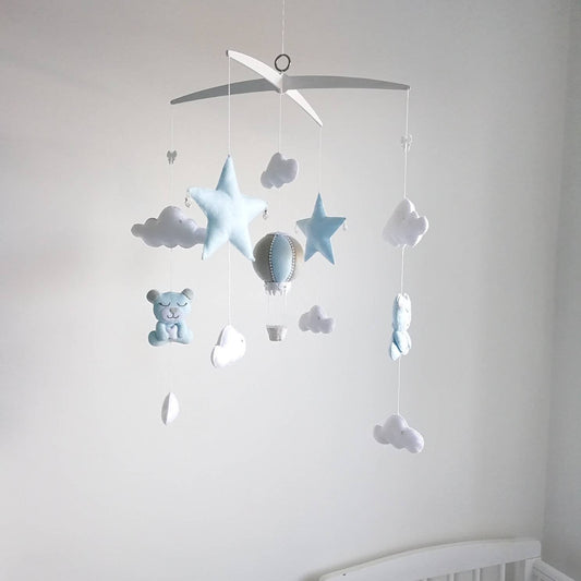 Handmade baby mobile with blue stars, white clouds, and a pale blue hot air balloon hanging from a cross hanger.

