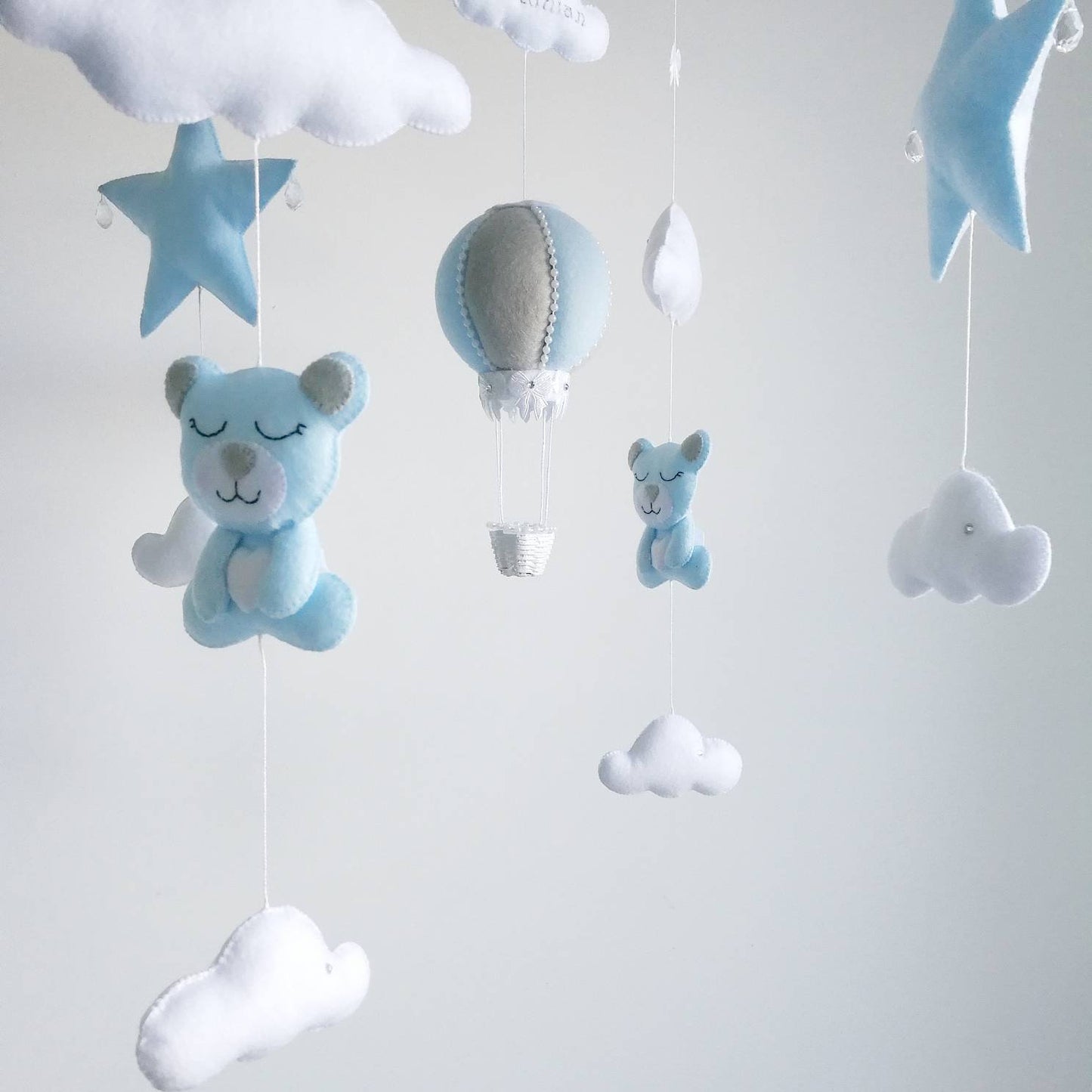 Baby boy mobile featuring blue teddy bears, stars, clouds, and hot air balloon in soft pastel tones.

